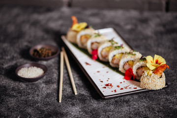 Various kinds of tasty sushi served on black stone