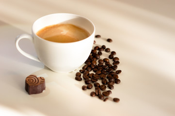 weiße Kaffeetasse mit Kaffee Schokolade und Kaffeebohnen auf weißen Hintergrund