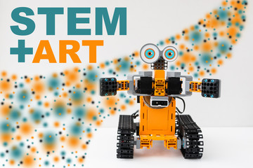 Orange plastic robot programmable on Scratch. STEM plus art is equal to STEAM. Science, technology, engineering, art, mathematics. The concept of new methods of teaching children and teenagers.