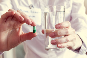 pill and a glass of water in the hands of a doctor