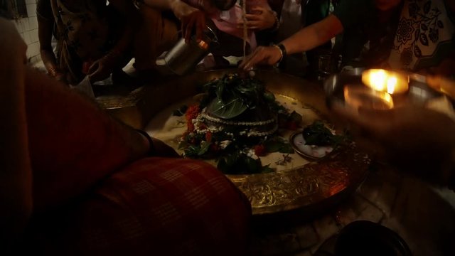 hands do puja rithual prayer with candle to swayambhu natural lingam another people put on shivlinga flowers leaves of bilva and prasad pour water and milk over it ancient hindu temple