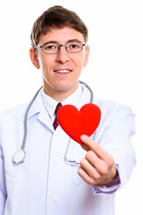 Close up of happy man doctor smiling while holding red heart