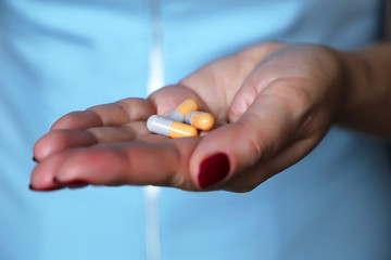 Pills in female palm close-up, woman doctor holding tablets in capsules. Concept of medicine, drugs, antibiotics, medical prescription