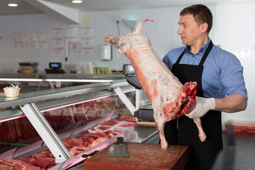 Butcher cutting lamb carcass