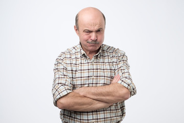 Senior man blowing his cheeks while being offended. Infantile behavior in adulthood
