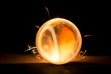 Burning sparkler behind a glass ball.