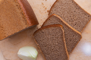 Slices of brick brown rye bread onion and salt on wooden background desk, top view, closeup