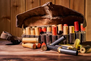 Muurstickers Old hunting cartridges and bandoleer on a wooden table © Vitalii Makarov