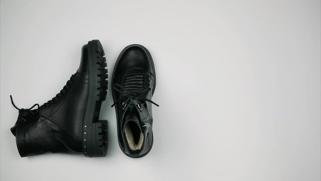 Black leather warm boots on a white background. Women's winter boots with rough soles. Stop motion