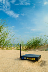 Obraz premium router on the sand on a summer day, the concept of modern technology, remote work, a network for freelancers