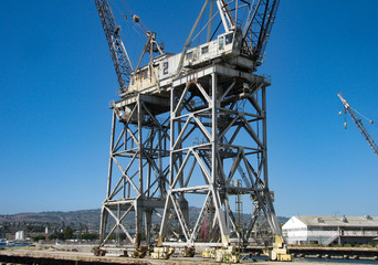 Fototapeta na wymiar Two inactive mobile gantry cranes, in an old ship yard. They loaded and unloaded cargo from ships at a port of the Pacific Ocean.