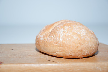 Hand cutting with a bun with a knife on a wooden chopping board