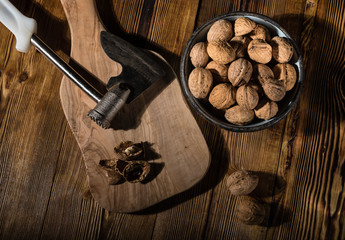 Walnuts in an old bowl with a kitchen ax on a wooden surface in rustic style