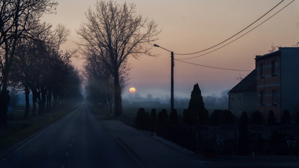 Morning in mystery village . Misty country road at dawn . 