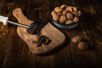 Walnuts in an old bowl with a kitchen ax on a wooden surface in rustic style