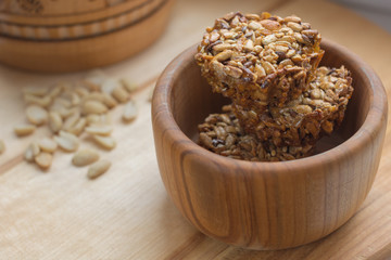 Roasted sunflower seeds in caramel and sugar in wooden bowl on wooden background. Front view.