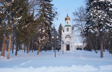 Small russian church in winter park at sunset