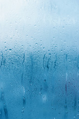 Window glass with high air humidity, large drops drip. Background of natural water condensation