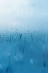 Window glass with high air humidity, large drops drip. Background of natural water condensation