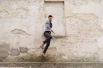 The young man jumping outdoor near the old house wall