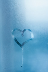 Heart on the glass and drops of water. Condensation on the window