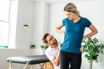 A Modern rehabilitation physiotherapy man at work with woman client working on hip