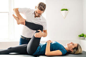 Fototapeta na wymiar A Modern rehabilitation physiotherapy man at work with woman client working on leg