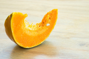 Slice of orange ripe pumpkin on wooden desk