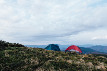 several tents spread out on mountain tops, gorgeous mountain landscapes are visible