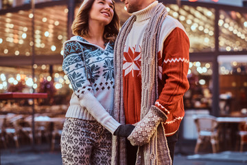 Cropped image of a romantic couple holding hands while standing on the street at Christmas time, enjoying spending time together.
