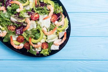 Mix of salad with shrimps , avocado and cherry tomatoes . Healthy food background