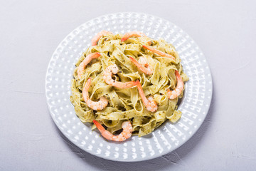 Pasta tagliatelle with sauce pesto and shrimps . Italian food background