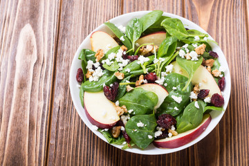 Autumn spinach salad with apple , cheese , walnut and dried cranberry . Healthy vegetarian food