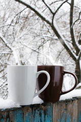 Two Cups of Hot Coffee or Tea on a Snow Covered Terrace.