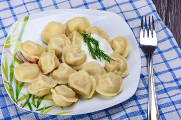 Portion of ravioli with sour cream and dill in a plate