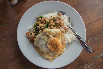 Close up rice topped with stir-fried pork and basil and fried Egg on white plate.Thai food style.(Khao Ka Prao Moo-Kai Dao)