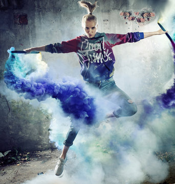 Portrait of a jumping dancer holding colorful flares