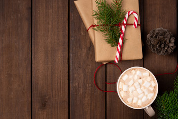 Holiday flatlay, gifts wrapped with craft paper, decorated with candy cane and cup mug of coffee cacao on a rustic dark wooden table. Space for text. Christmas concept. New Year concept. Gifts
