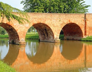 old bridge made of red bricks with the river