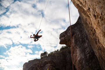 Man in hardhat hanging on rope while doing rappel and showing pirouettes flying in air © pablobenii