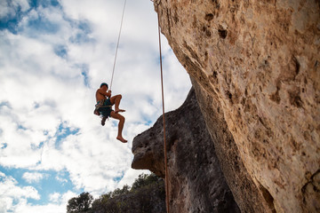 Man in hardhat hanging on rope while doing rappel and showing pirouettes flying in air © pablobenii