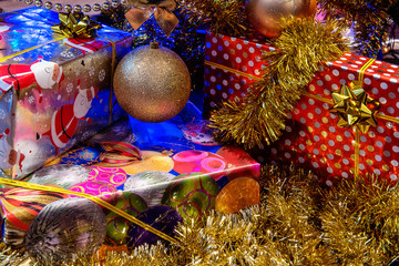 Fototapeta na wymiar The gift boxes wrapped in paper under the Christmas tree. The New Year presents. Winter holidays background.