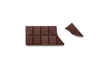 Broken dark chocolate bar isolated on white table. Horizontal composition. Top view