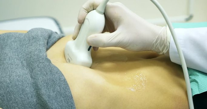 Doctor making a ultrasound diagnostic of stomach. Looking to thin abdomen of young women at ultrasound device screen on the hospital