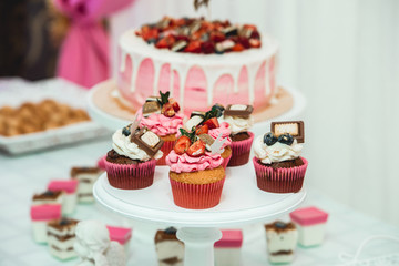 white stand with cupcakes on a candy bar table