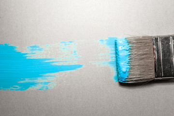 paint brush in blue paint on an unpainted flat surface, copyspace