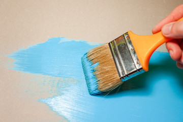 paint brush in hand paints with blue paint