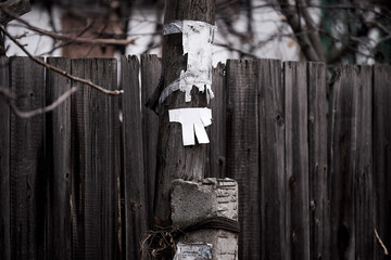wooden pole with empty paper standing near a wooden fence