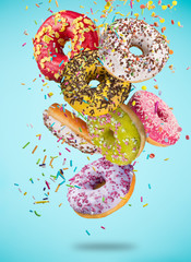 Tasty doughnuts in motion falling on pastel blue background.