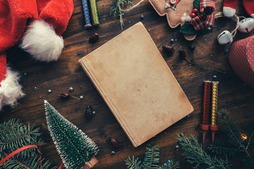 Vintage book among Christmas decoration, flat lay top view
